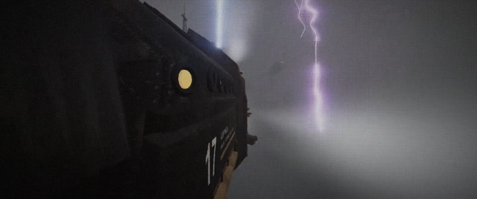 Close along Hauler 17's dark bow in the storm, a violet lightning bolt striking the fog behind her.